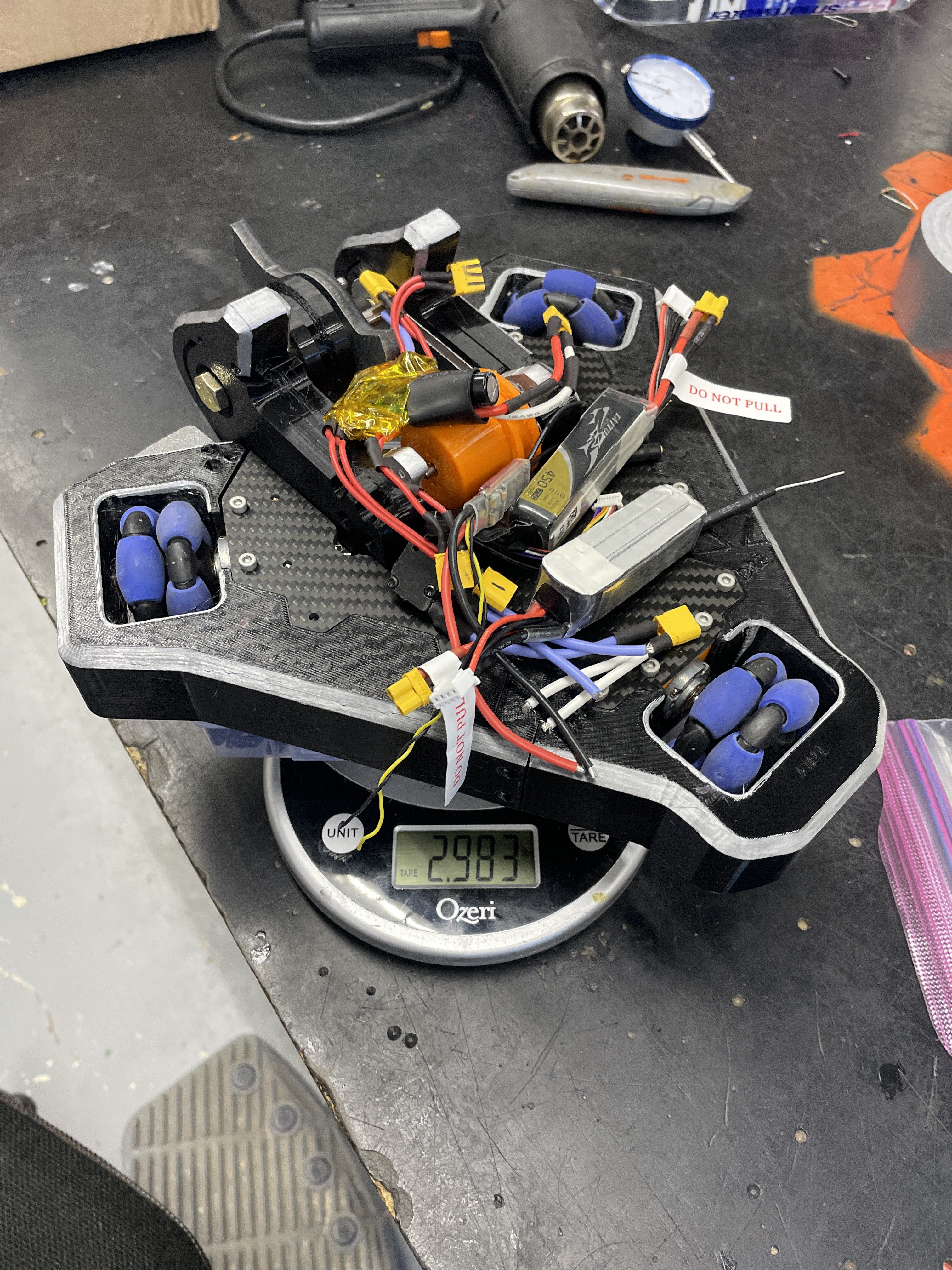 Clu on a scale with electronics piled on top, scale reads 2.983lb
